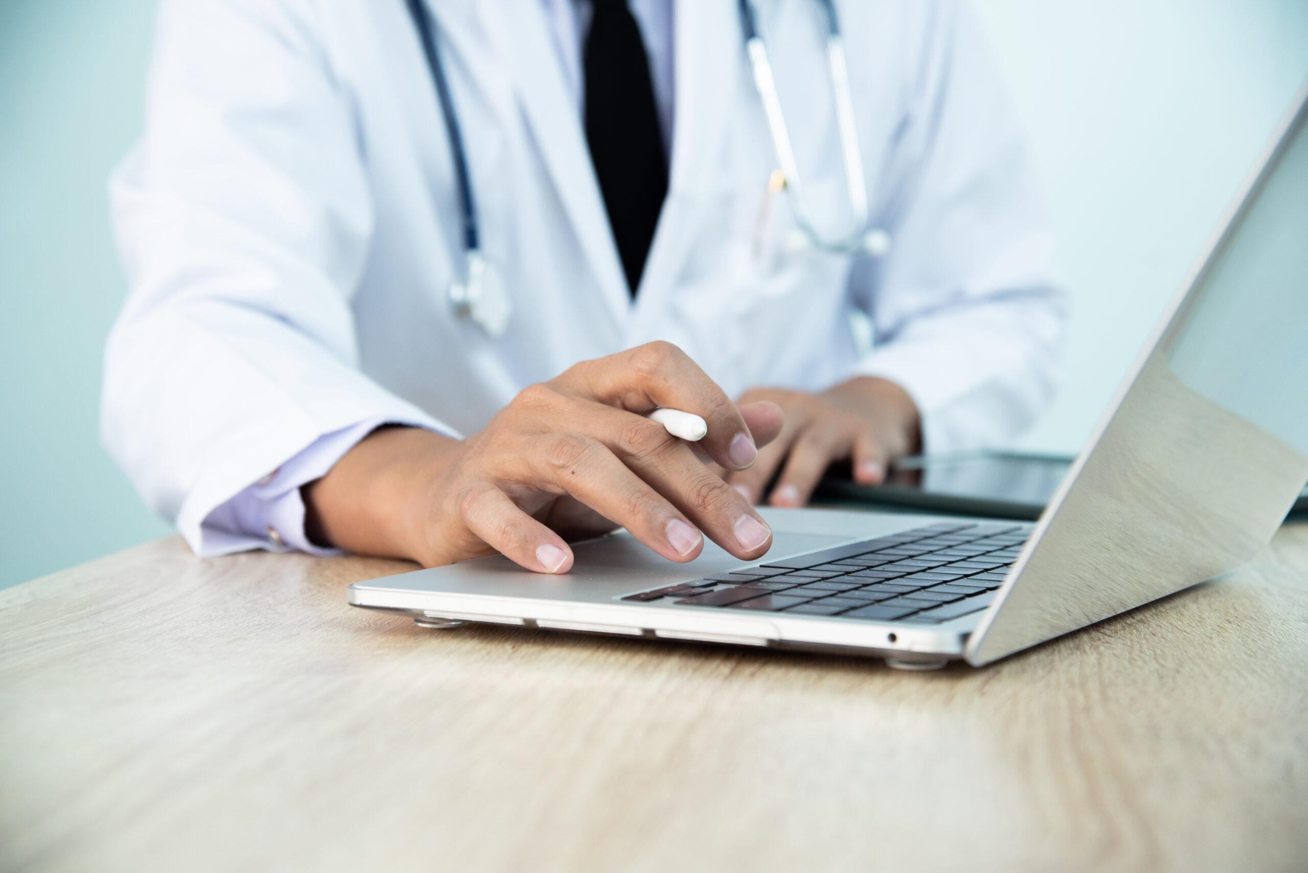 In the hospital, doctor using laptop for medical professionals to access patient information, manage medical records, and stay up-to-date with medical research and developments. Physician input data.