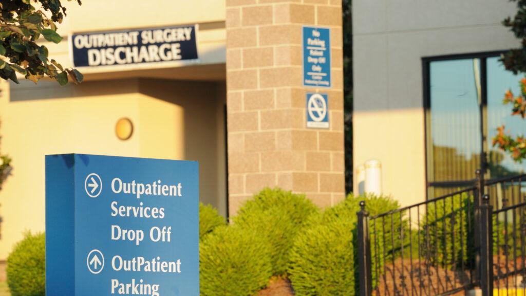 Directional sign for outpatient services drop off and parking near entrance and discharge to outpatient building at hospital.