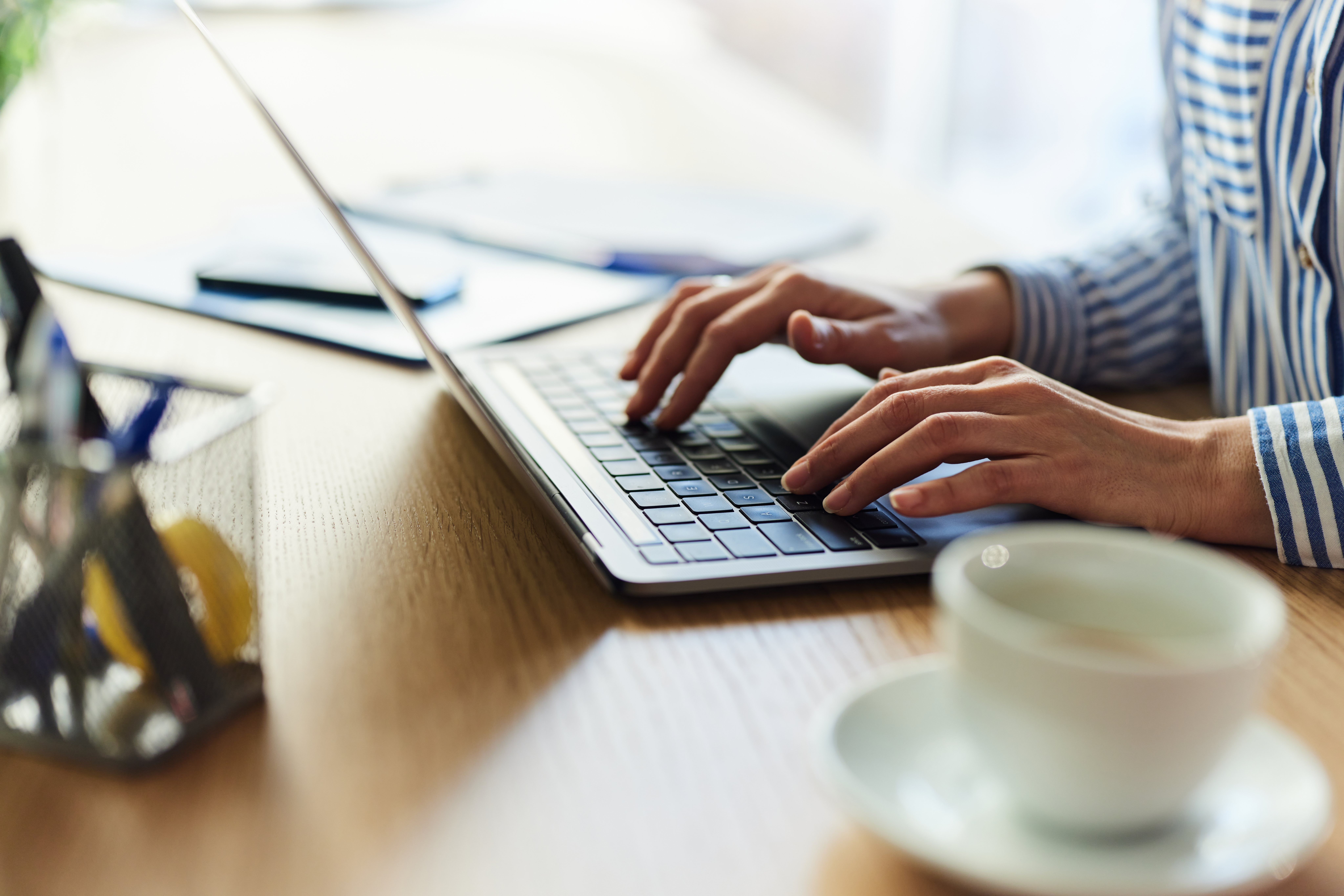 Close up of a female entrepreneur typing an email on a computer in the office.