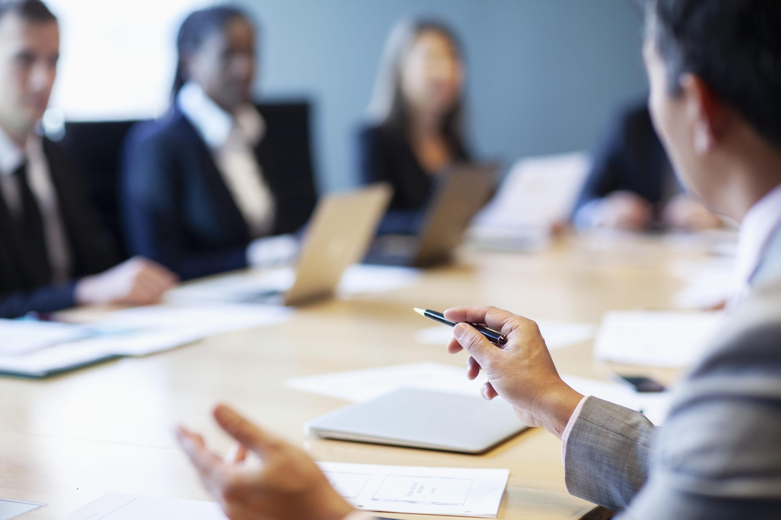 Hands of businessman gesturing ideas decisions with pen pointing leadership to work colleagues in business meeting at board room conference table