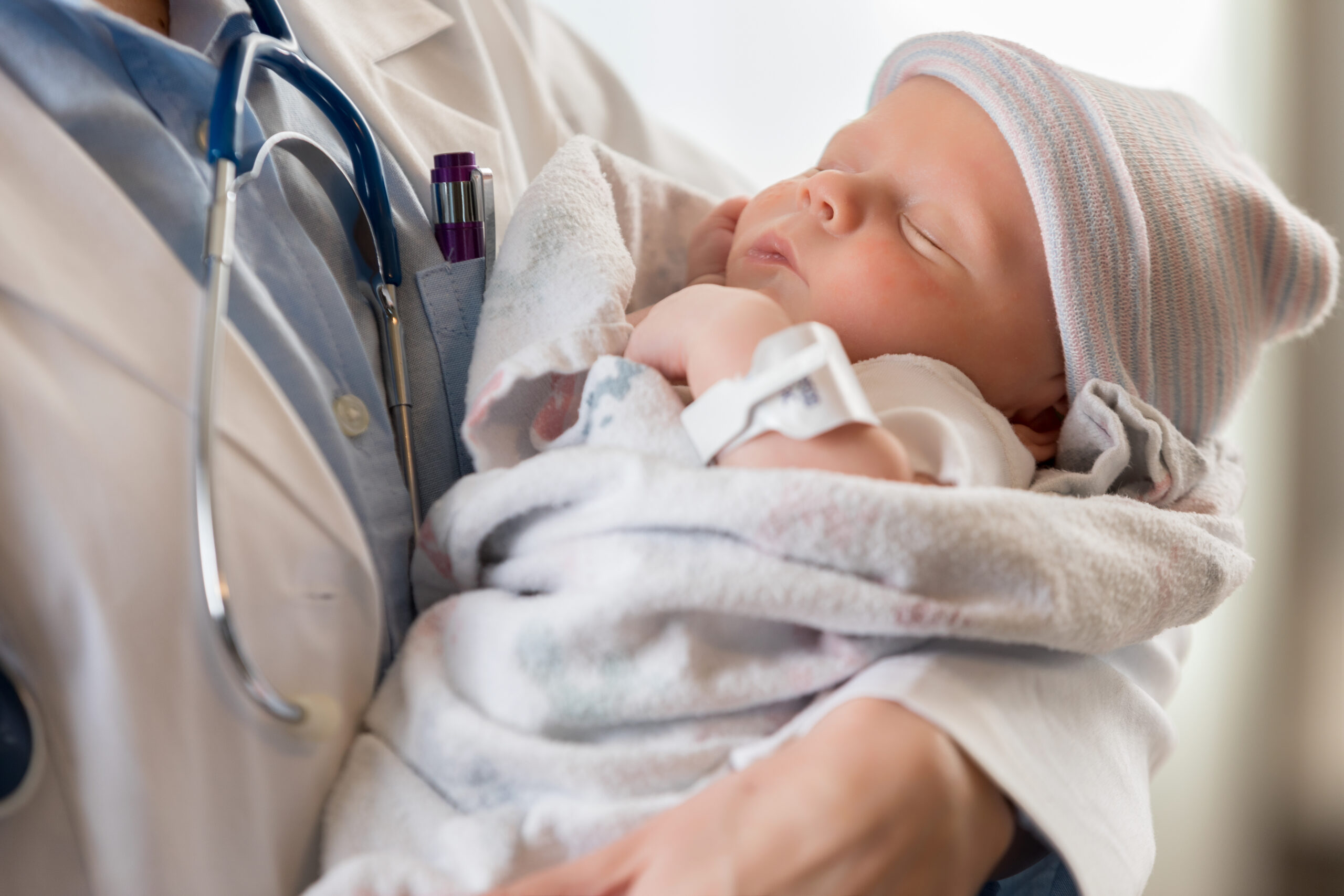 Healthcare professional holds a sleeping newborn baby, symbolizing care, medical expertise, and the beginning of life.